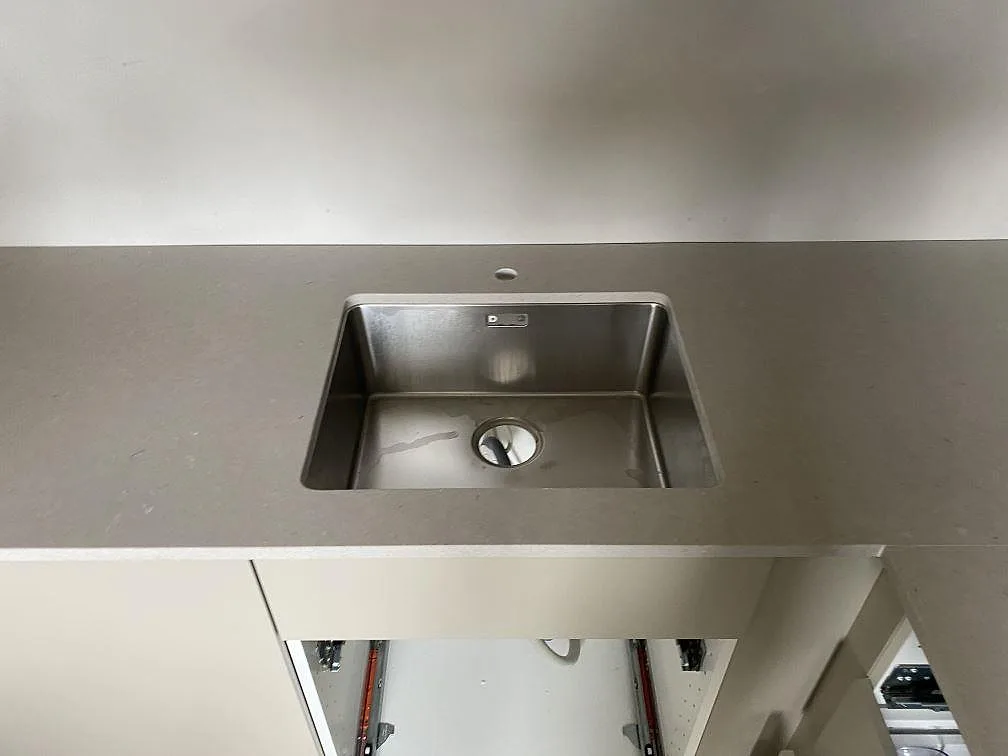 Köksbänkskiva i greigebeige Silestone Royal Reef, matt, med underlimmad rostfri diskho i ett kök i Malmö.