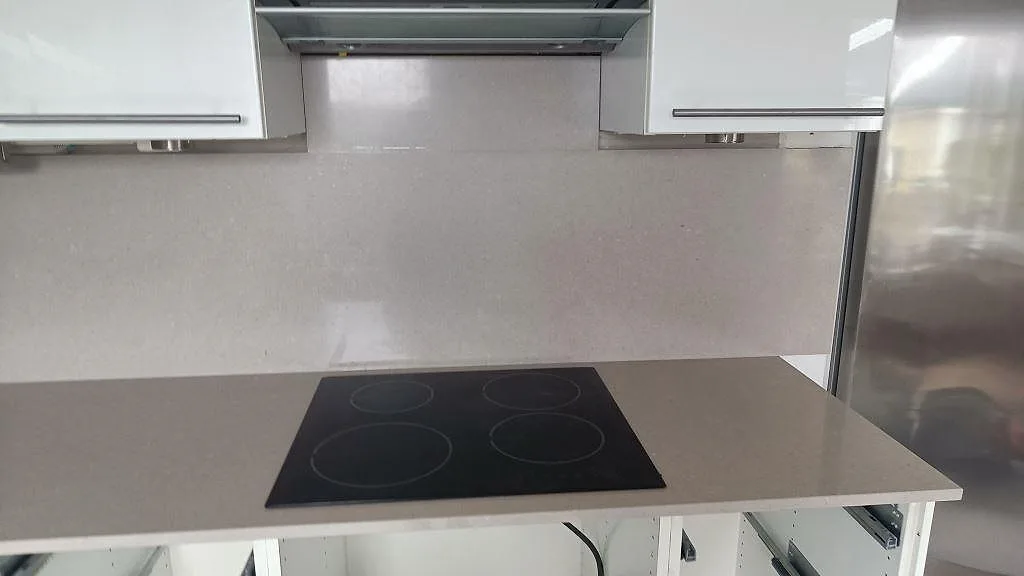 Svart häll infälld i polerad Silestone Royal Reef med matchande stänkskydd i ett kök i Malmö.