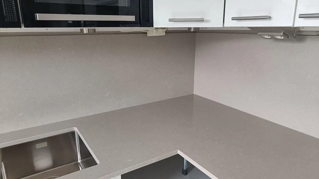 Hörnparti i polerad Silestone Royal Reef med diskho, stänkskydd och ljus köksinredning i Malmö.