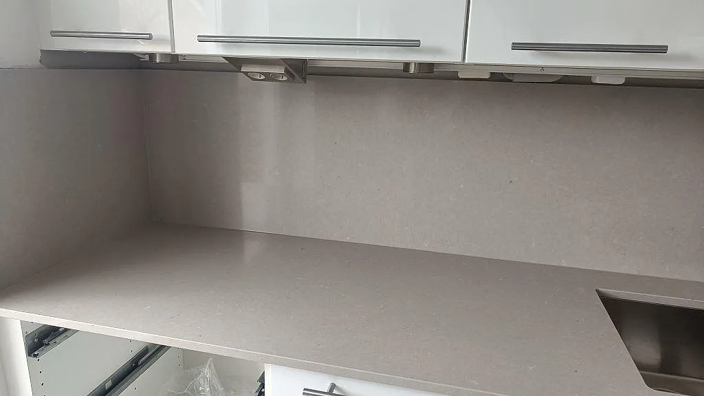 Sidobänk i polerad Silestone Royal Reef med diskho och stänkskydd under vita överskåp i Malmö.