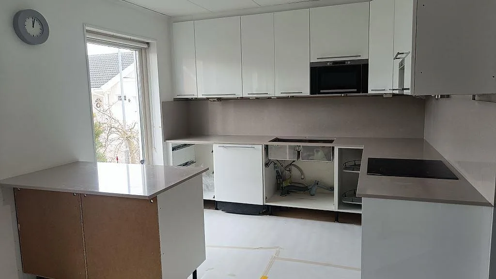 Köksbänkskiva i taupefärgad Silestone Royal Reef, polerad, i ett U-format kök med vit skåpinredning i Malmö.