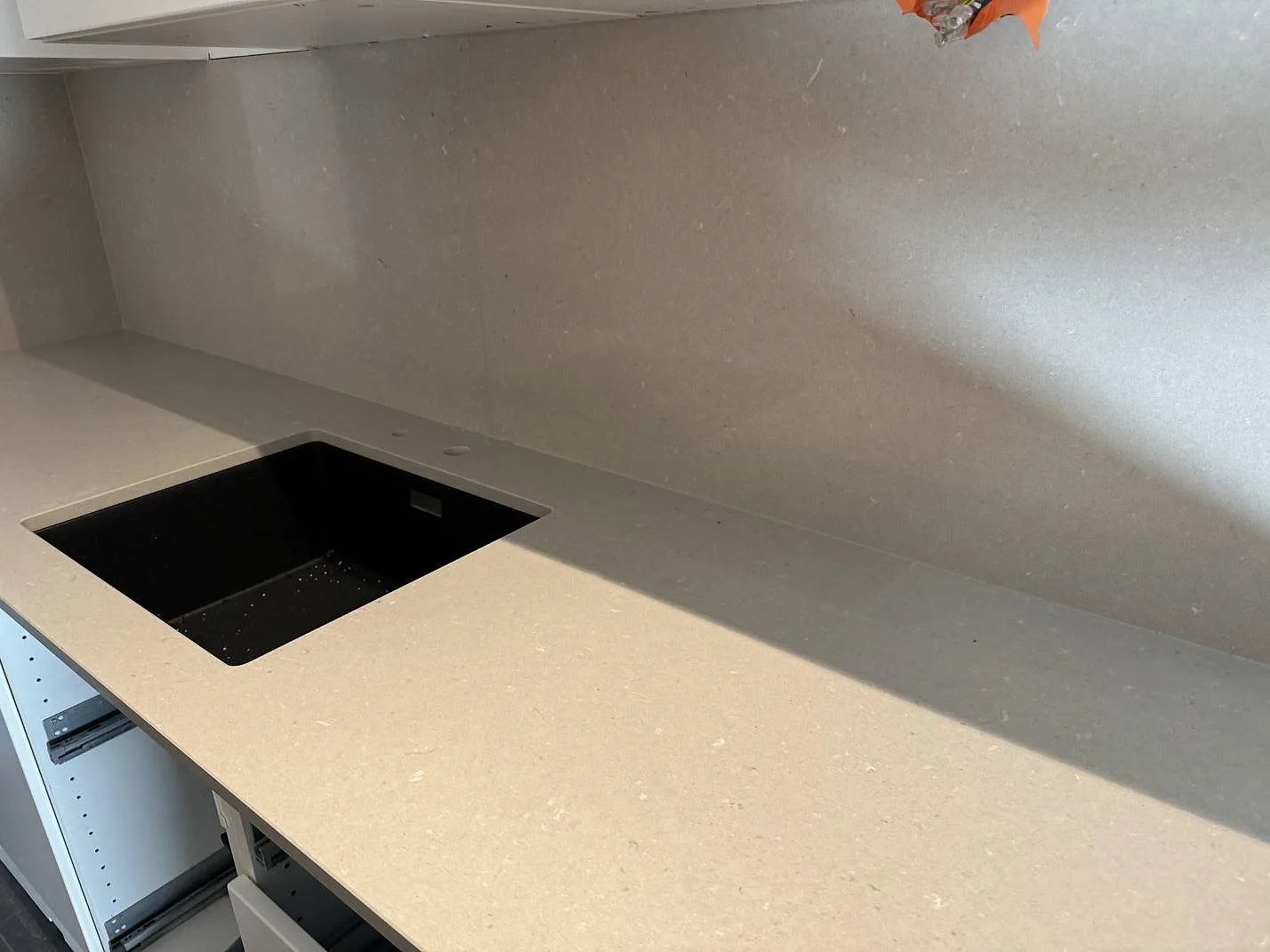 Närbild av polerad Silestone Royal Reef, kvartskomposit, som köksbänkskiva och stänkskydd med svart diskho i Malmö.