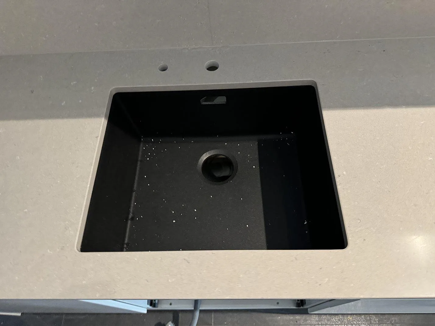 Detalj av svart diskho i polerad Silestone Royal Reef, kvartskomposit, med blandarhål i ett kök i Malmö.