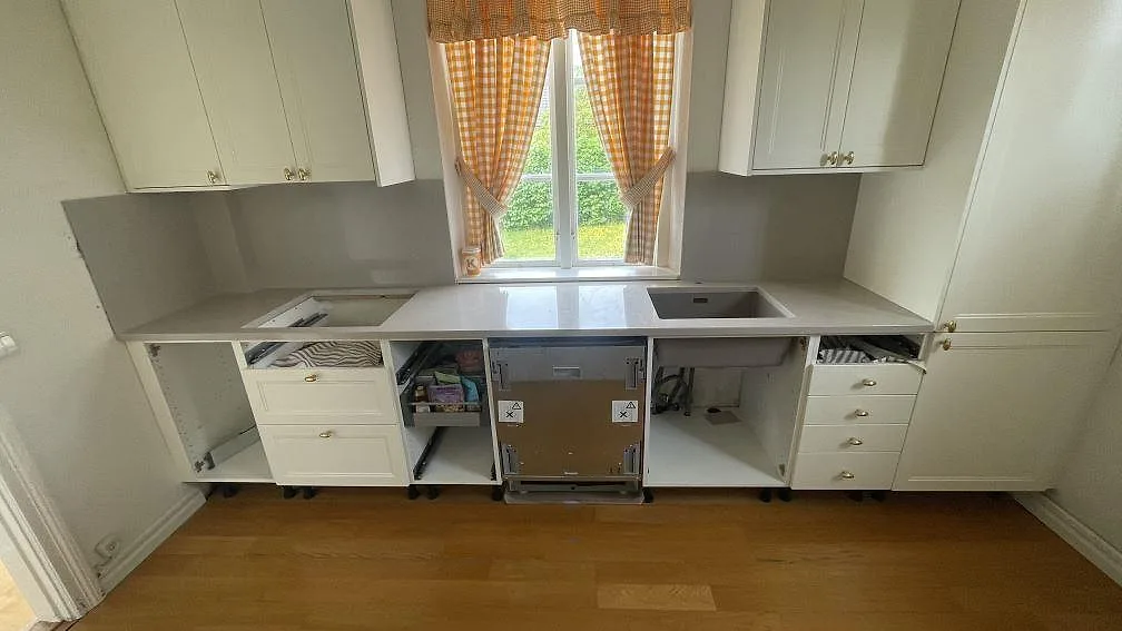 Köksbänkskiva i polerad Silestone Royal Reef, gråbeige kvartskomposit, monterad längs köksväggen i ett kök i Malmö.