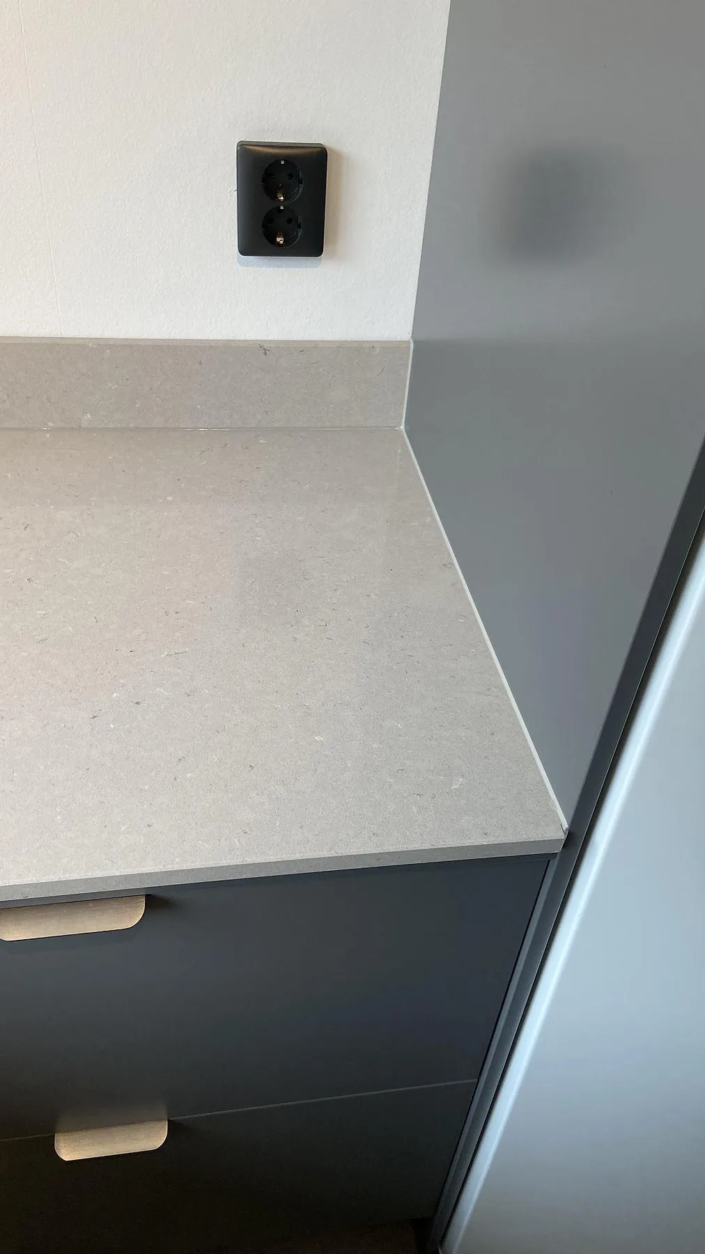 Köksbänkskiva i polerad Silestone Royal Reef med uppvikt stänkkant och ljus beige yta i ett kök i Oxie.