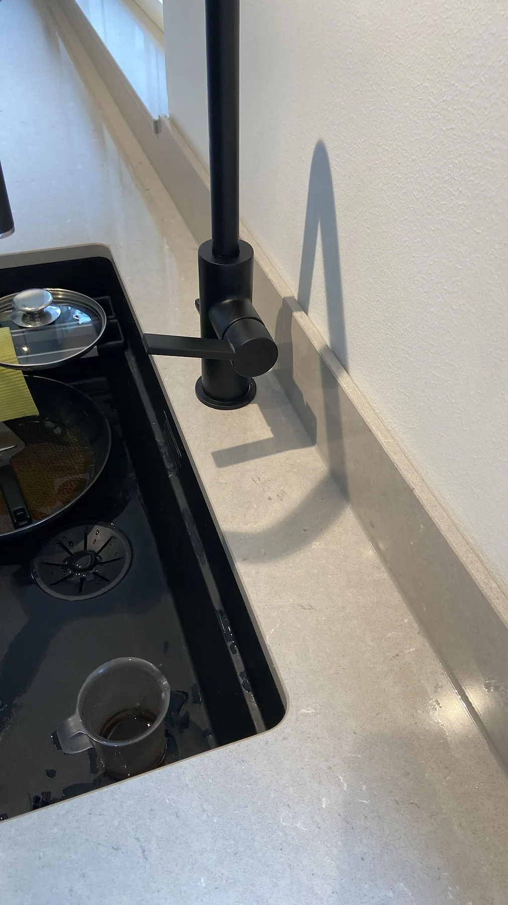 Detalj av infälld häll och svart köksblandare på en polerad Silestone Royal Reef bänkskiva i ett kök i Oxie.