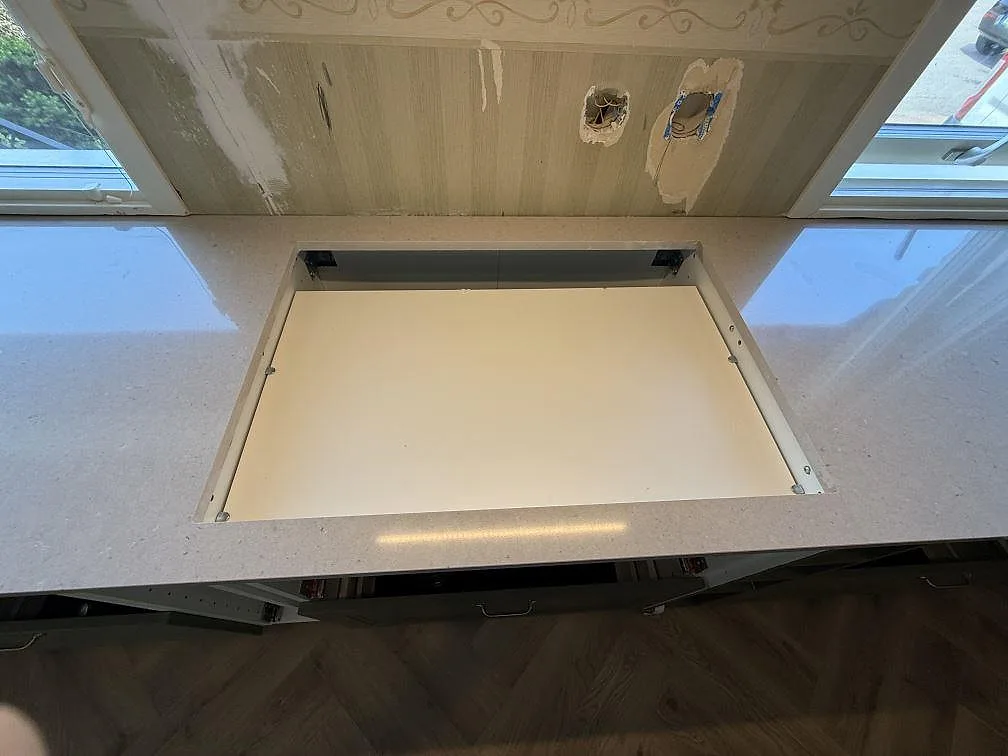 Köksbänkskiva i polerad Silestone Royal Reef med öppning för spishäll mellan två fönster i Skänninge.