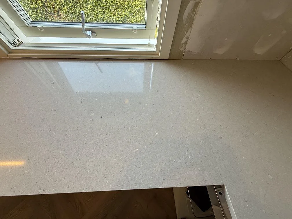 Perimeterbänk i polerad Silestone Royal Reef vid köksfönster, ljus kvartskomposit i Skänninge.
