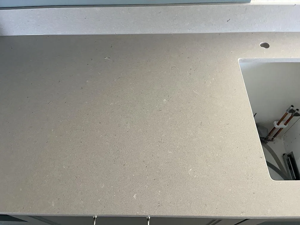 Närbild av matt gråbeige Silestone Royal Reef med diskhoutsparing och fönstersida i kök i SKANÖR.