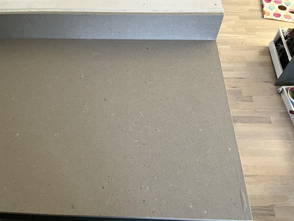 Köksbänkskiva i matt Silestone Royal Reef med gråbeige komposityta, stänkkant och trägolv i ett kök i SKANÖR.