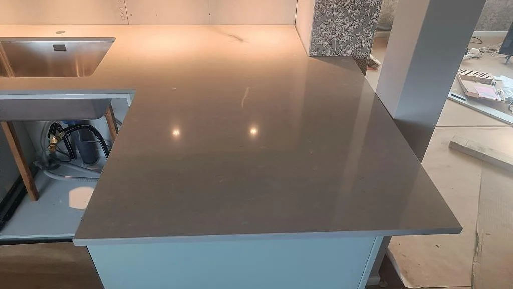 Närbild på polerad Silestone Royal Reef som köksödel med rostfri diskho och ljus skåpinredning i Skillingaryd.