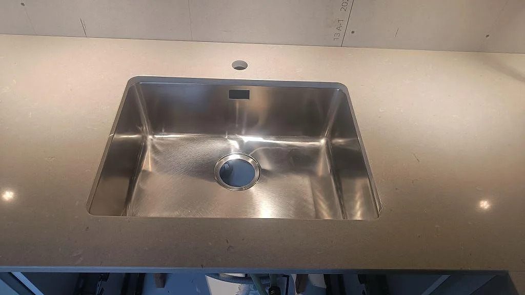 Underlimmad rostfri diskho monterad i polerad Silestone Royal Reef på köksbänkskiva i Skillingaryd.