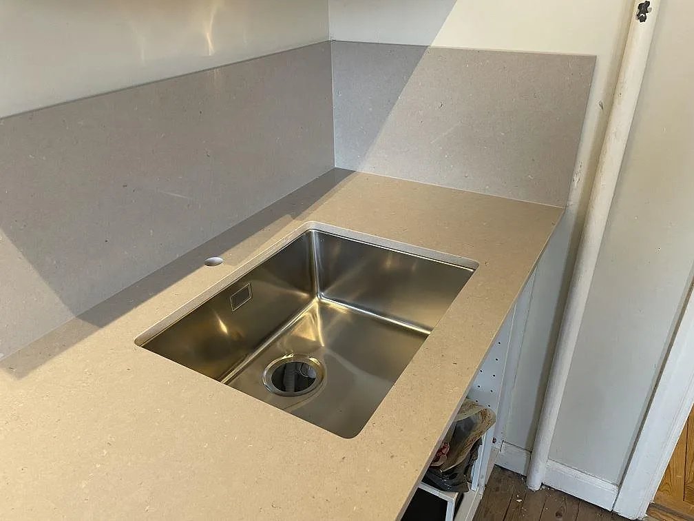 Underlimmad rostfri diskho infälld i polerad Silestone Royal Reef med lågt uppvikt stänkskydd i ett kök i Stockholm.
