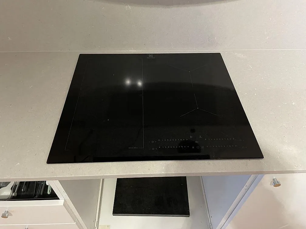 Svart Electrolux induktionshäll nedfälld i ljust beige Silestone Royal Reef köksbänkskiva i ett kök i Stockholm.