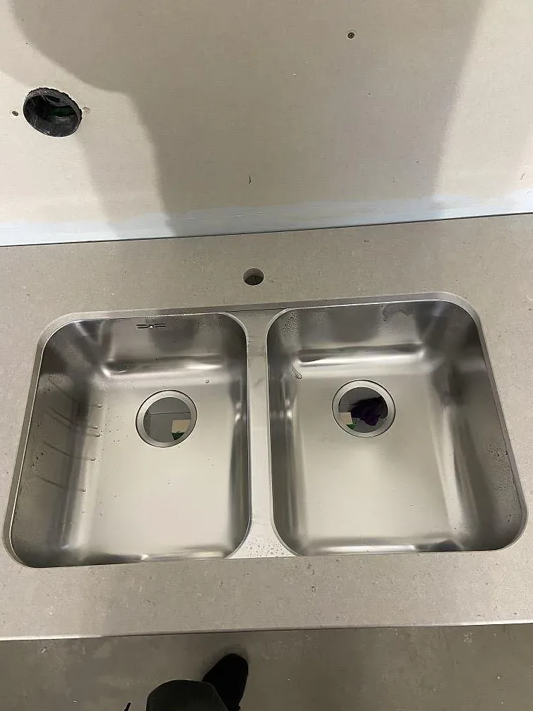 Underlimmad rostfri dubbelho i en polerad bänkskiva av Silestone Royal Reef med separat borrat blandarhål, i ett kök i Tjurkö.