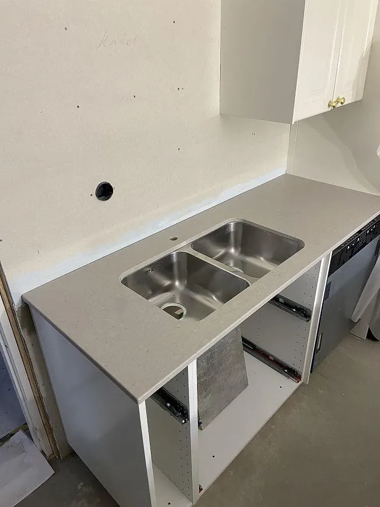 Bänkrad i Silestone Royal Reef med underlimmad rostfri ho över öppna köksstommar under montering i Tjurkö.