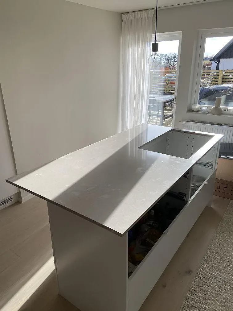 Köksö i greige Silestone Royal Reef med infälld induktionshäll, matt yta, i ett ljust kök i Trelleborg.