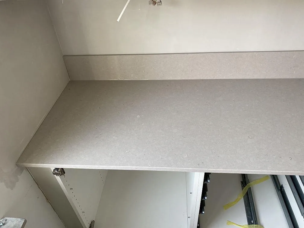 Närbild på polerad Silestone Royal Reef-bänkskiva och uppvikt stänkkant i ett kök under montering i Trelleborg.