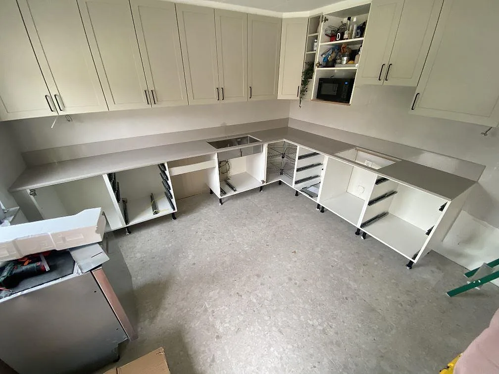 Köksbänkskiva i beige Silestone Royal Reef, polerad kvartskomposit, monterad i L-form längs ett kök under montering i Trelleborg.