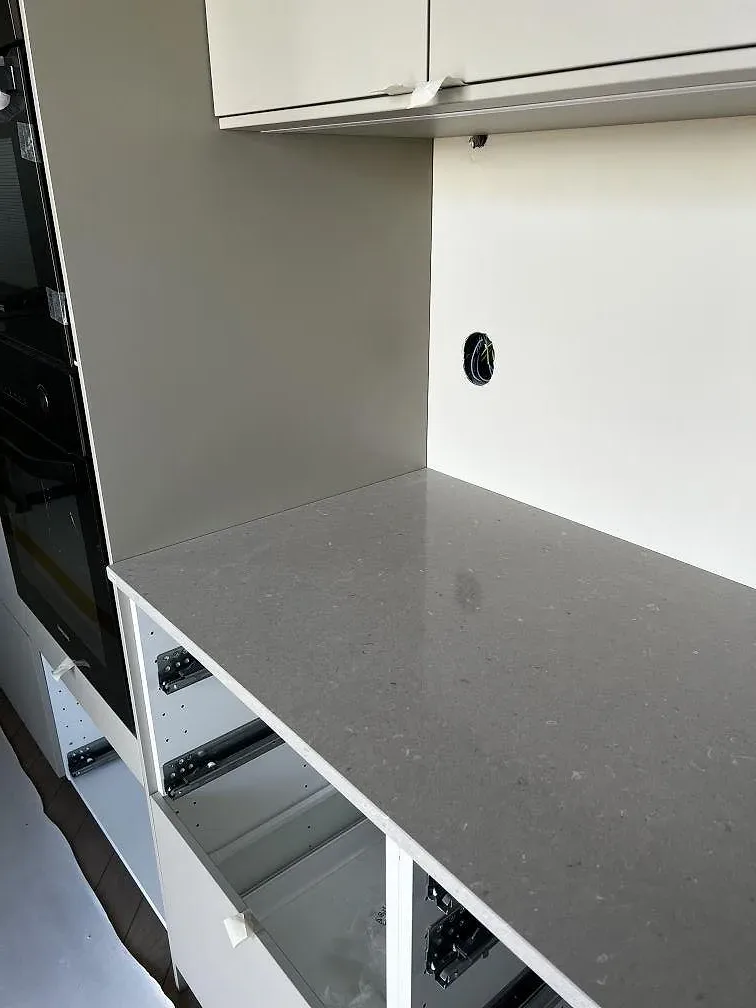 Närbild av polerad Silestone Royal Reef bänkskiva och 12 mm stänkskydd vid vita köksskåp i Trelleborg.