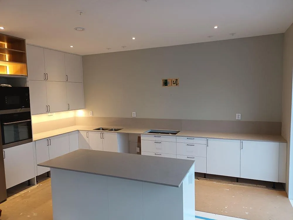 Köksbänkskiva i beige Silestone Royal Reef, polerad, med matchande köksö i ett U-format kök under montering i Tullinge.