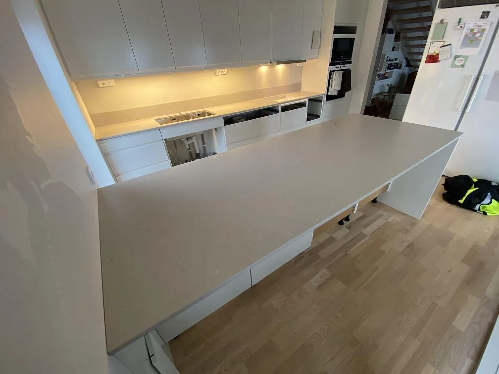 Köksbänkskiva och köksö i Silestone Royal Reef Mocka med ljus kompositsten i ett kök under montering i Tygelsjö.