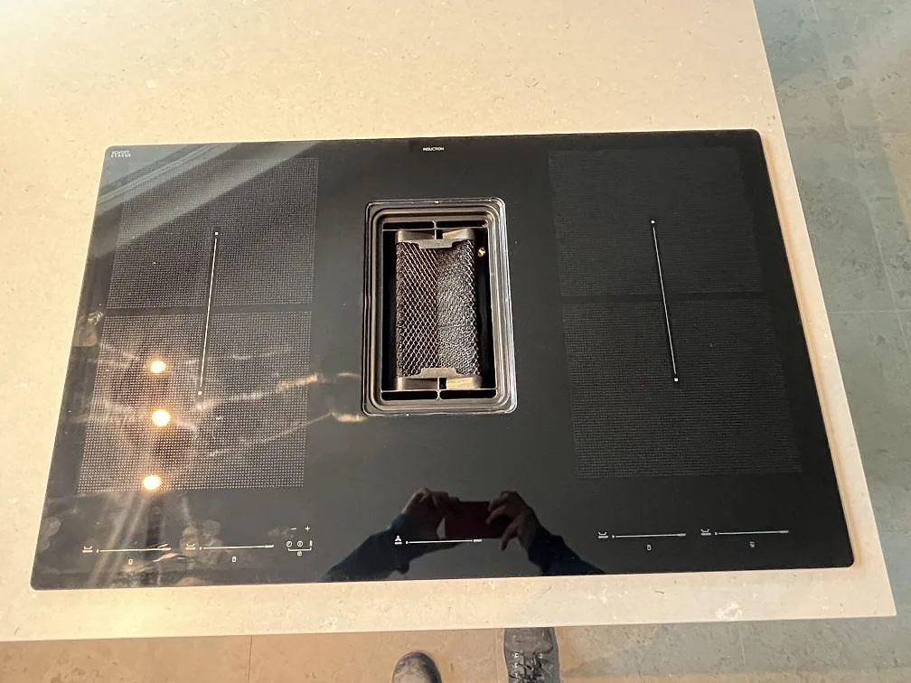 Närbild på svart induktionshäll monterad i köksö med matt Silestone Royal Reef komposit som bänkskiva i Tyresö.