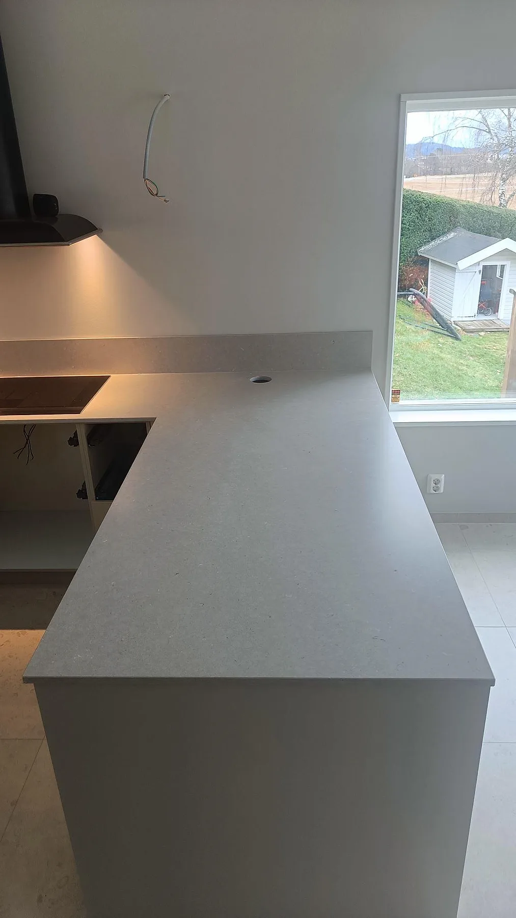 Närbild av köksö i matt Silestone Royal Reef med rund kabelgenomföring och fönsterljus i ett kök i Uddevalla.