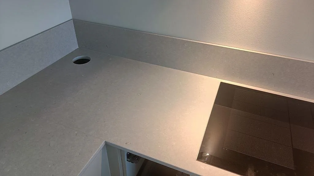 Detalj av matt Silestone Royal Reef runt häll och kabelgenomföring med låg stänkkant i köket i Uddevalla.