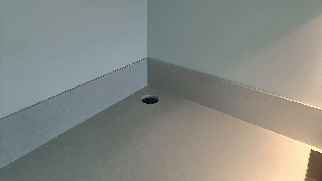 Hörnparti i matt Silestone Royal Reef med rund genomföring och låg stänkkant under väggbelysning i Uddevalla.
