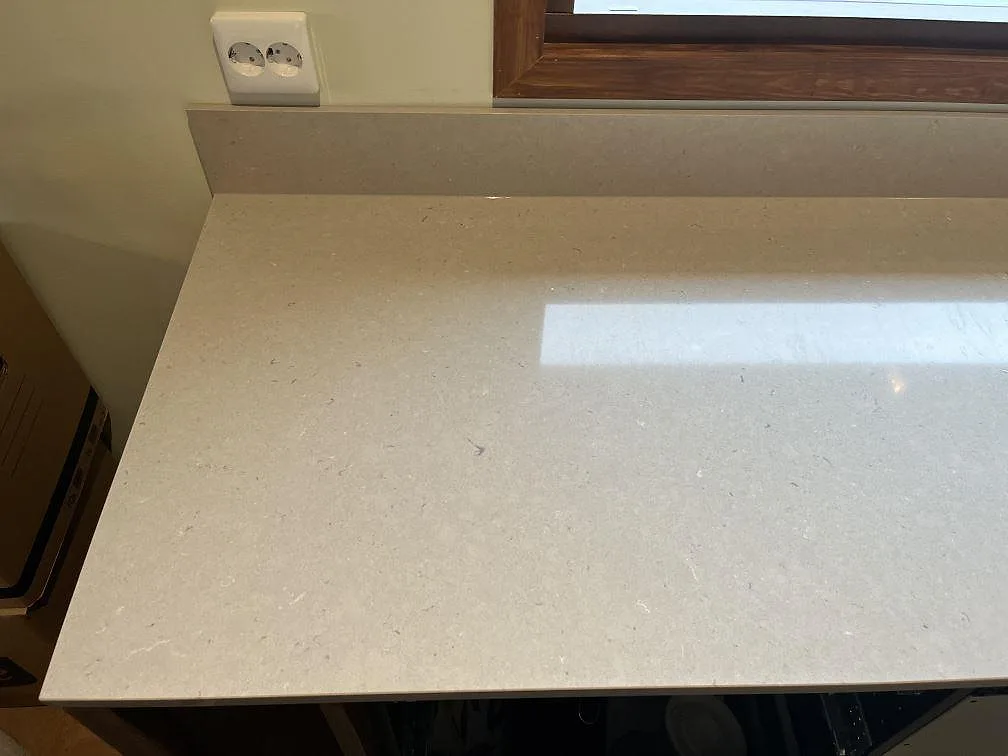 Detalj av polerad Silestone Royal Reef bänkskiva med uppvikt stänkkant vid ett fönster i Växjö.