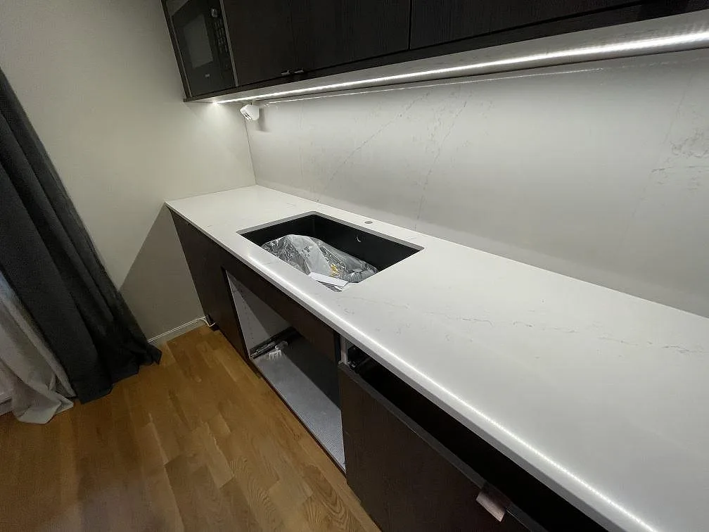 Närbild av polerad Silestone Siberian frost som köksbänkskiva med öppning för diskho och stänkvägg i samma material i Bromma.