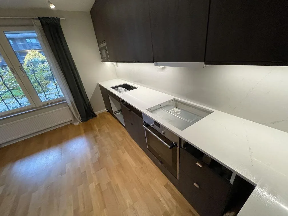 Lång köksbänkskiva i polerad Silestone Siberian frost med väggbeklädnad, diskhoöppning och hällöppning i Bromma.