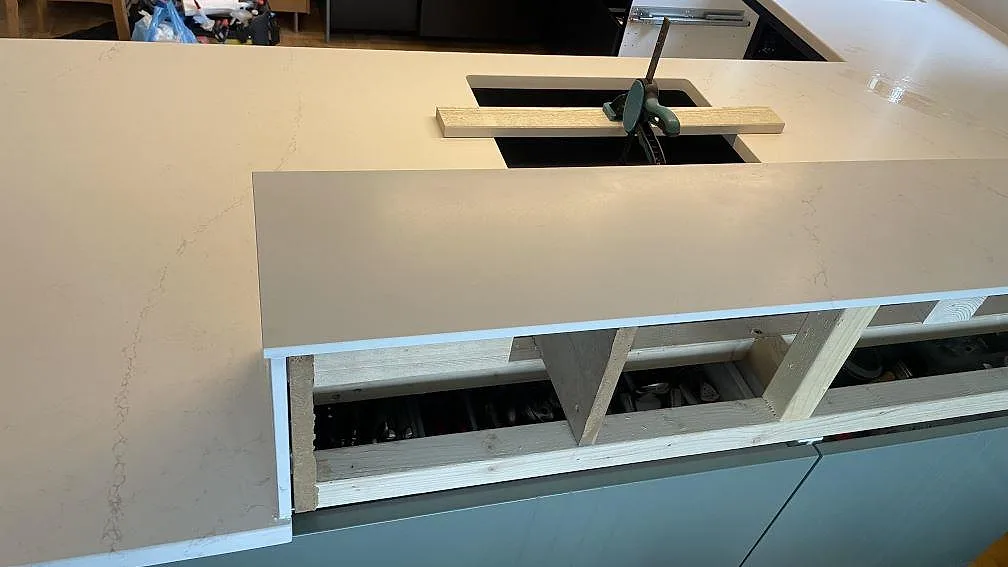 Detalj av köksbänkskiva i matt Silestone Siberian frost med uppbyggd stenkant och svart diskhoöppning under montering i Jönköping.