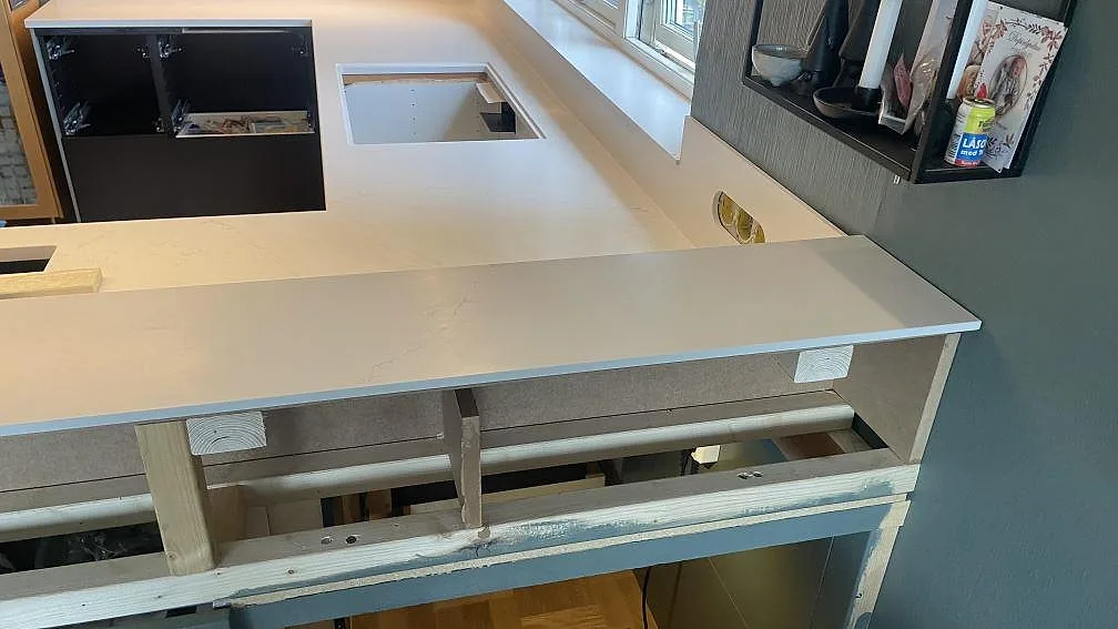 L-formad köksbänkskiva i matt Silestone Siberian frost vid fönster, med förberedd öppning och låg stänkkant i Jönköping.