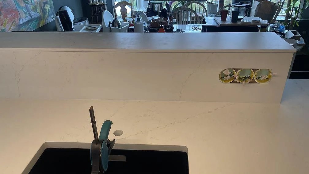 Närbild av stänkskydd och arbetsyta i matt Silestone Siberian frost med uttagshål och svart diskho under montering i Jönköping.