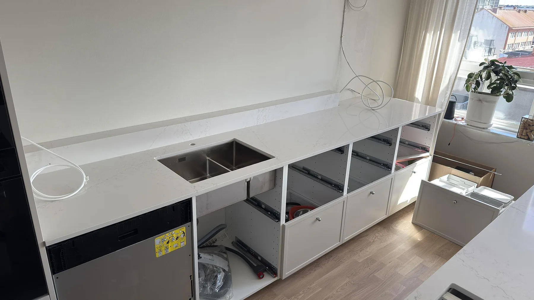 Underlimmad rostfri diskho i polerad Silestone Siberian frost med grå ådring längs bänkraden i ett kök i Karlstad.