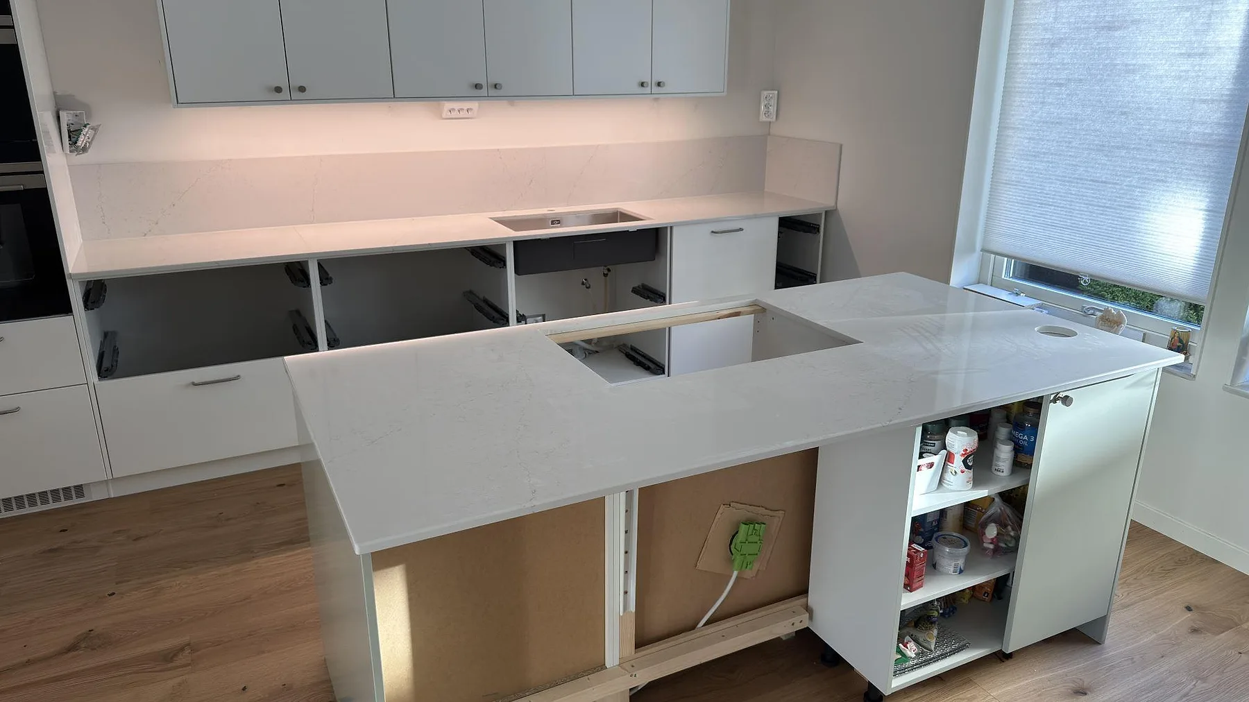 Polerad Silestone Siberian frost som köksö och väggbänk med stänkskydd, synlig diskho och hällurtagning i Norrköping.