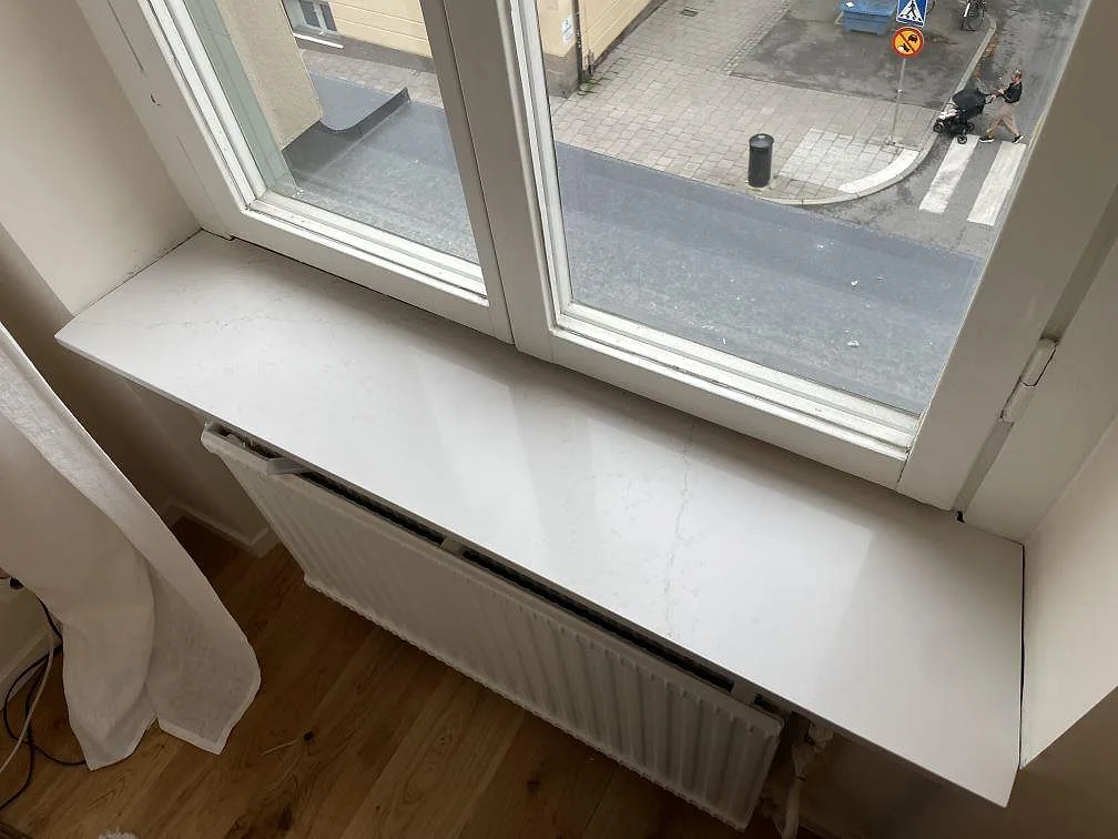 Närbild på fönsterbänk i polerad Silestone Siberian Frost med diskret ådring vid ett fönster i Stockholm.