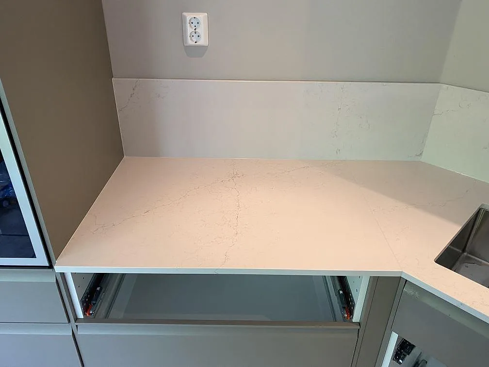 Vänster bänkyta i polerad Silestone Siberian frost med ljus ådring och stänkskydd i ett kök i Veberöd.