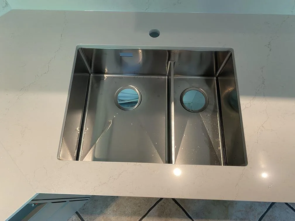 Närbild på diskho i polerad Silestone Siberian frost, ljus kvartskomposit med grå ådring i ett kök i Veberöd.