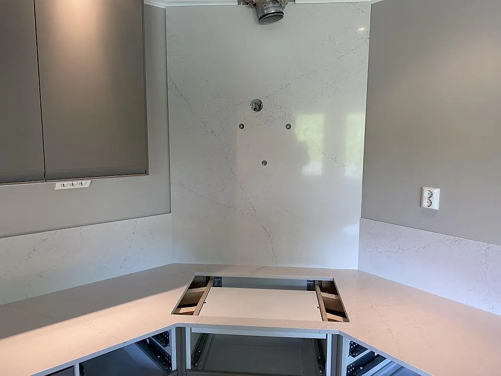 Hällöppning och högre väggpanel i polerad Silestone Siberian frost bakom arbetsytan i ett kök i Veberöd.
