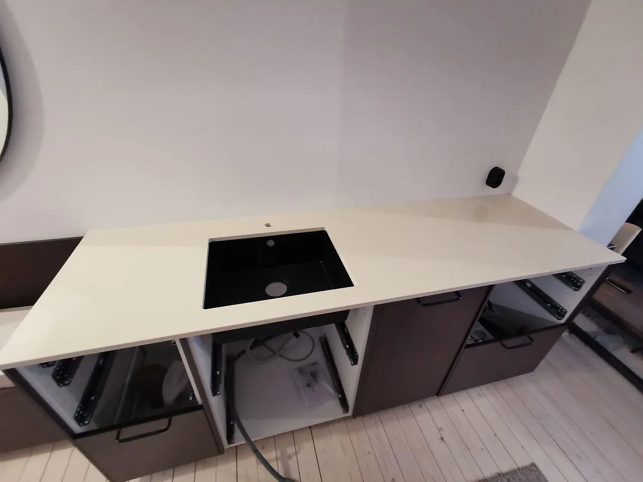 Köksbänkskiva i Silestone Silken Pearl, polerad greige komposit, med svart underlimmad kompositdiskho i ett kök under montering i Malmö.