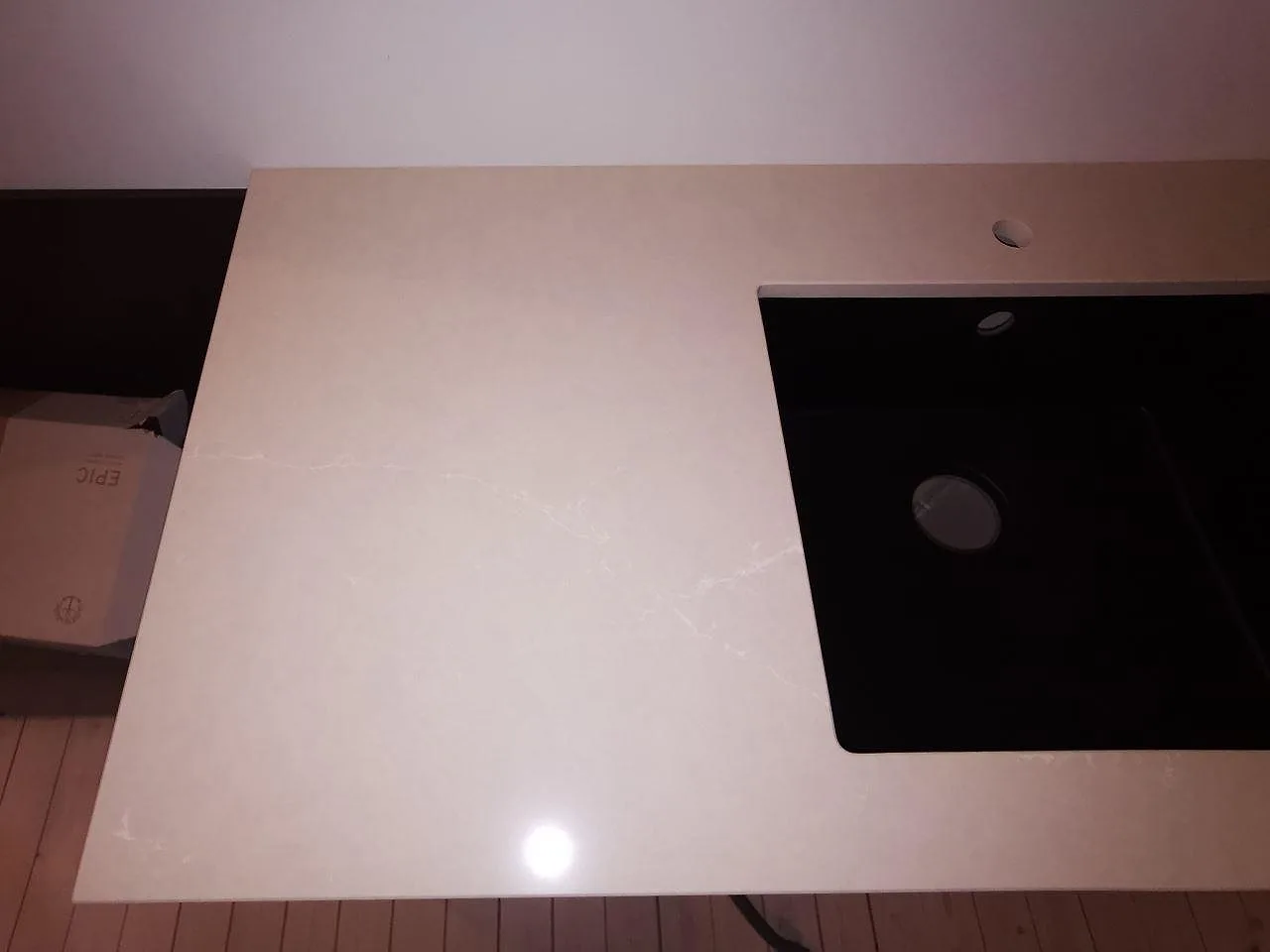 Närbild på greige Silestone Silken Pearl bänkskiva med svart underlimmad diskho och blandarehål i ett kök i Malmö.
