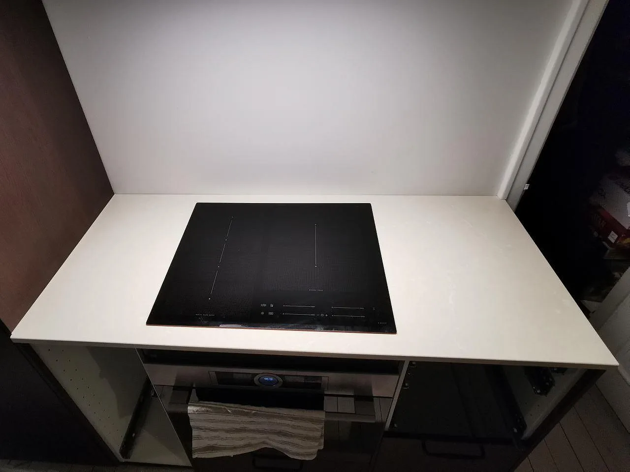 Polerad Silestone Silken Pearl köksbänkskiva med övermonterad induktionshäll ovanpå stenen i ett kök i Malmö.
