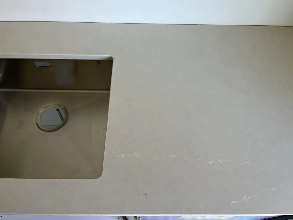 Köksbänkskiva i Silestone Silken Pearl med underlimmad rostfri diskho och urtag för induktionshäll i ett kök i Staffanstorp.