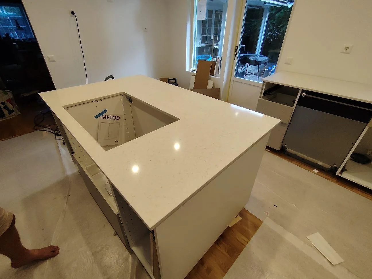 Stor köksö i polerad Silestone Snowy Ibiza med rektangulär öppning och ljus ådring i ett kök i Åkersberga.