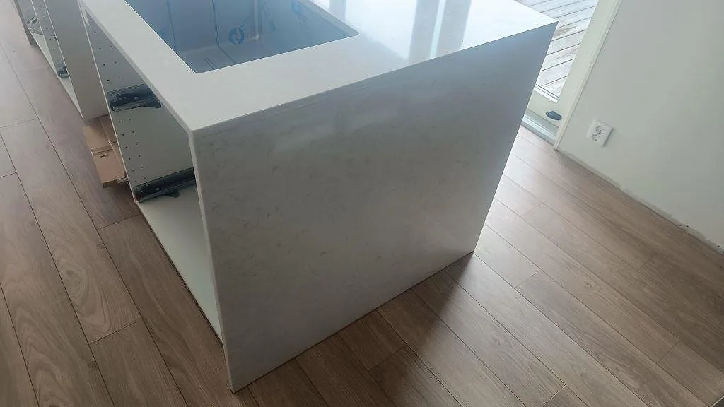 Vattenfallssida på vit köksö i polerad Silestone Snowy Ibiza med diskho i ett kök i Åskloster.