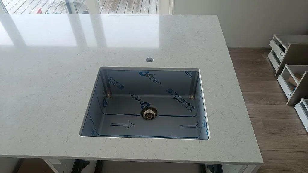 Närbild på underlimmad rostfri diskho i polerad Silestone Snowy Ibiza med vit komposityta i Åskloster.