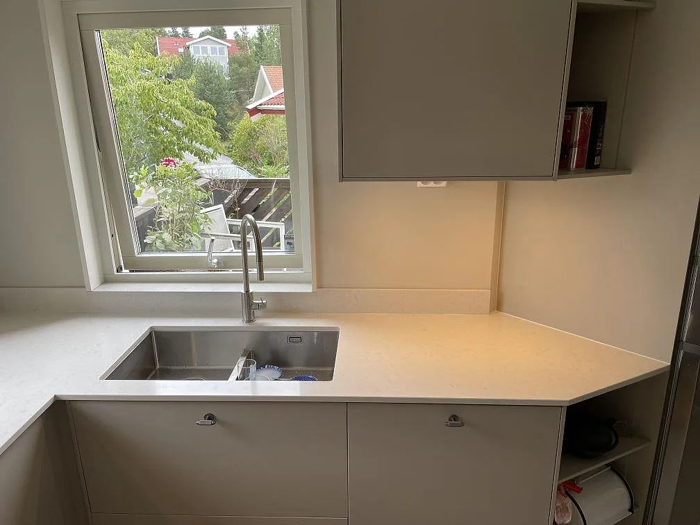 Diskhozonen i ett kök i Älta med polerad Silestone Snowy Ibiza-bänkskiva, synlig diskho och ljus kvartskomposityta.